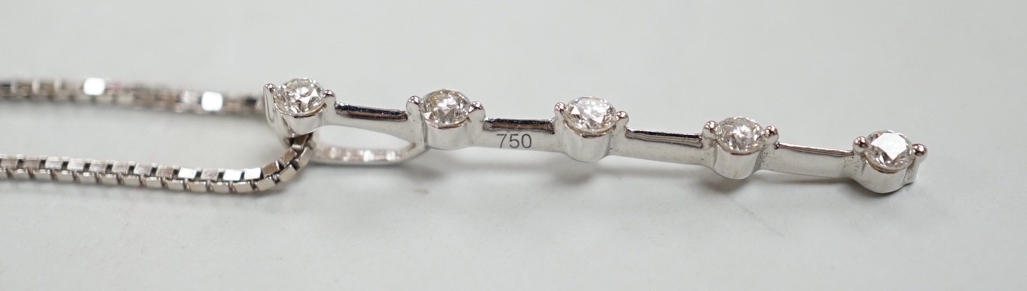 A modern 750 white metal and five stone diamond chip set line pendant, 25mm, on an 18kt white metal fine link chain, 40cm, gross weight 2.9 grams.
